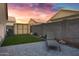 Private backyard with artificial grass, storage shed, and a lounge chair under a colorful sunset at 2629 E Hidalgo Ave, Phoenix, AZ 85040
