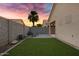 Private backyard with artificial grass, pavers, lounge chair and desert plants under a colorful sunset at 2629 E Hidalgo Ave, Phoenix, AZ 85040