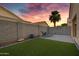 Private backyard featuring artificial grass, a lounge chair, and desert plants under a colorful sunset at 2629 E Hidalgo Ave, Phoenix, AZ 85040