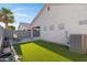 A manicured backyard with artificial turf, a chaise lounge, and a perimeter block fence for privacy at 2629 E Hidalgo Ave, Phoenix, AZ 85040