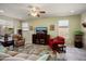 Comfortable living room with a TV and ceiling fan, featuring tile floors and a floral rug at 26456 W Cat Balue Dr, Buckeye, AZ 85396