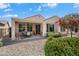 Covered patio with outdoor dining set, overlooking a decorative rock yard with vibrant greenery and colorful plants at 26456 W Cat Balue Dr, Buckeye, AZ 85396