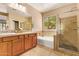 Bright bathroom featuring double sinks, tub and glass-enclosed shower and a window for natural light at 29703 N 70Th Ave, Peoria, AZ 85383