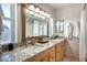 Bright bathroom featuring dual sinks, granite countertops, and framed mirror at 7001 E Flossmoor Ave, Mesa, AZ 85208