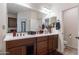Bathroom featuring dual vanity, mirrors, dark wood cabinets, and red flower decorations at 720 E Cobble Stone Dr, Queen Creek, AZ 85140