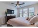 Bedroom with a ceiling fan, TV, three windows, and a dark wood dresser at 720 E Cobble Stone Dr, Queen Creek, AZ 85140