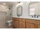 Modern bathroom with double sink vanity, sleek mirrors, and a walk-in shower with glass enclosure at 7647 E Montecito Ave, Scottsdale, AZ 85251