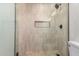 Close up of shower with neutral tile, glass enclosure, black hardware and tiled shower floor at 7647 E Montecito Ave, Scottsdale, AZ 85251