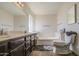Bathroom featuring a double sink dark wood vanity, soaking tub, and a neutral color palette at 7844 W Jenan Dr, Peoria, AZ 85345