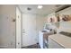 Functional laundry room with modern washer and dryer units, shelving for supplies, and door to outside at 7844 W Jenan Dr, Peoria, AZ 85345