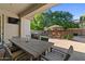 Covered backyard patio with an outdoor dining area, TV, and lush landscaping at 834 W Whitten St, Chandler, AZ 85225