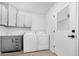 Well-lit laundry room with white cabinets, washer, and dryer next to the side door at 855 S Revolta Cir, Mesa, AZ 85208