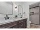 Bathroom featuring double sink vanity with marble countertop, dark wood cabinets, and tiled shower in the background at 862 W Rawhide Ave, Gilbert, AZ 85233