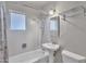Full bathroom showcasing a pedestal sink, white tile, tub with shower, and updated fixtures at 101 W 8Th Pl, Mesa, AZ 85201