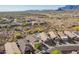 Desert community aerial view showcases a pool, tan houses, desert landscaping and mountains in the distance at 10276 E Meandering Trail Ln, Gold Canyon, AZ 85118