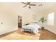 The bright bedroom features wood floors, ceiling fan, a bed with a white comforter, and large windows at 10276 E Meandering Trail Ln, Gold Canyon, AZ 85118