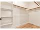 Spacious walk-in closet with white shelving, wooden rods, and stylish woodgrain floors at 10276 E Meandering Trail Ln, Gold Canyon, AZ 85118