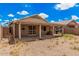 Expansive backyard featuring a covered patio, desert landscaping, and a block fence for privacy at 12034 W Aster Dr, El Mirage, AZ 85335
