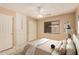 Stylishly staged bedroom with tile floors, ceiling fan, built-in storage, and a window overlooking the backyard at 12034 W Aster Dr, El Mirage, AZ 85335