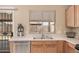 This kitchen features tile floors, light wood cabinets, stainless steel appliances, and a window over the sink at 12034 W Aster Dr, El Mirage, AZ 85335
