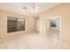 Bright, tiled living room features a ceiling fan, a large window, and open access to the front door at 12034 W Aster Dr, El Mirage, AZ 85335
