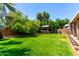 Large backyard with mature trees, grassy area, and covered hot tub at 13213 W Jacobson Dr, Litchfield Park, AZ 85340