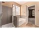An ensuite bathroom features a glass-enclosed shower and a soaking tub, creating a spa-like experience at 13213 W Jacobson Dr, Litchfield Park, AZ 85340