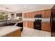 A well-equipped kitchen features wood cabinetry, black appliances, and a convenient breakfast bar, all set against a tile floor at 13213 W Jacobson Dr, Litchfield Park, AZ 85340