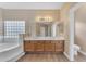 Bright bathroom featuring a tub, wood cabinets and a large mirror at 13304 W Palo Verde Dr, Litchfield Park, AZ 85340