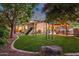 This backyard features a playset, lush green grass, mature trees, and a gazebo with seating at 1356 E Flamingo Ct, Gilbert, AZ 85297