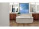 Lovely bathroom with a large tub, dual vanities, warm lighting, and a window with a beautiful blue privacy screen at 1356 E Flamingo Ct, Gilbert, AZ 85297
