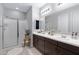 Elegant bathroom with dual sinks, dark wood cabinets, a glass-enclosed shower, and neutral tile flooring at 17084 N Palo Pino St, Maricopa, AZ 85138