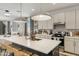 Spacious kitchen boasts an island with a sink, pendant lighting, modern appliances, and white cabinetry at 17084 N Palo Pino St, Maricopa, AZ 85138