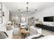 Living room with a modern chandelier, white furniture, dark console, open to the dining room and kitchen at 17084 N Palo Pino St, Maricopa, AZ 85138