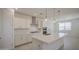 Open kitchen features white cabinets, island, stainless appliances, and pendant lights at 17803 W Elm St, Goodyear, AZ 85395