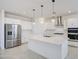Modern kitchen with stainless steel appliances, white cabinetry, and a large center island with pendant lighting at 17803 W Elm St, Goodyear, AZ 85395
