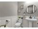 Powder room with pedestal sink, round mirror, wainscoting, and decorative wall art at 20165 E Via Del Palo Dr, Queen Creek, AZ 85142