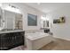 Bright bathroom features a soaking tub, dual vanities with granite countertops, and a decorative TV at 20165 E Via Del Palo Dr, Queen Creek, AZ 85142