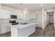 Well-lit kitchen with an island and stainless appliances, complemented by stylish wood-look flooring at 25283 N 183Rd Dr, Wittmann, AZ 85361