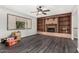 Living room featuring a cozy fireplace with wood and brick accents, plus a large window and modern ceiling fan at 3201 W Evans Dr, Phoenix, AZ 85053