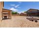 Desert backyard featuring a covered patio and a trampoline against a backdrop of blue skies at 44175 W Knauss Dr, Maricopa, AZ 85138