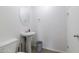 Clean and modern half-bathroom featuring a pedestal sink, a toilet, and a stylish oval mirror at 44175 W Knauss Dr, Maricopa, AZ 85138