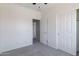 Bright carpeted bedroom with white walls, ceiling fan, closet, and interior door at 44175 W Knauss Dr, Maricopa, AZ 85138
