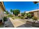 Tranquil backyard with landscaped garden beds, a well-manicured lawn, and a concrete walkway leading through the greenery at 6018 W Villa Maria Dr, Glendale, AZ 85308