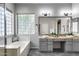 Bright bathroom featuring dual sinks, a large soaking tub, and a glass block window at 6742 W El Cortez Pl, Peoria, AZ 85383