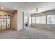 Spacious living room with neutral carpeting, an arched doorway, and natural light from large windows at 6742 W El Cortez Pl, Peoria, AZ 85383