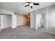 Open-concept living area featuring an arched doorway, neutral carpeting, and custom wooden built-ins at 6742 W El Cortez Pl, Peoria, AZ 85383