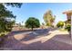 Spacious manicured backyard with mature trees, landscaping, and view of neighboring houses at 7220 E Edgewood Ave, Mesa, AZ 85208