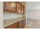 Kitchen featuring wood cabinets, granite countertops, and a seamless transition to the adjacent carpeted living space at 7973 S Peppertree Ct, Gilbert, AZ 85298