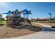 Community playground with slides, climbing structures, and shaded seating areas on woodchip ground at 7973 S Peppertree Ct, Gilbert, AZ 85298